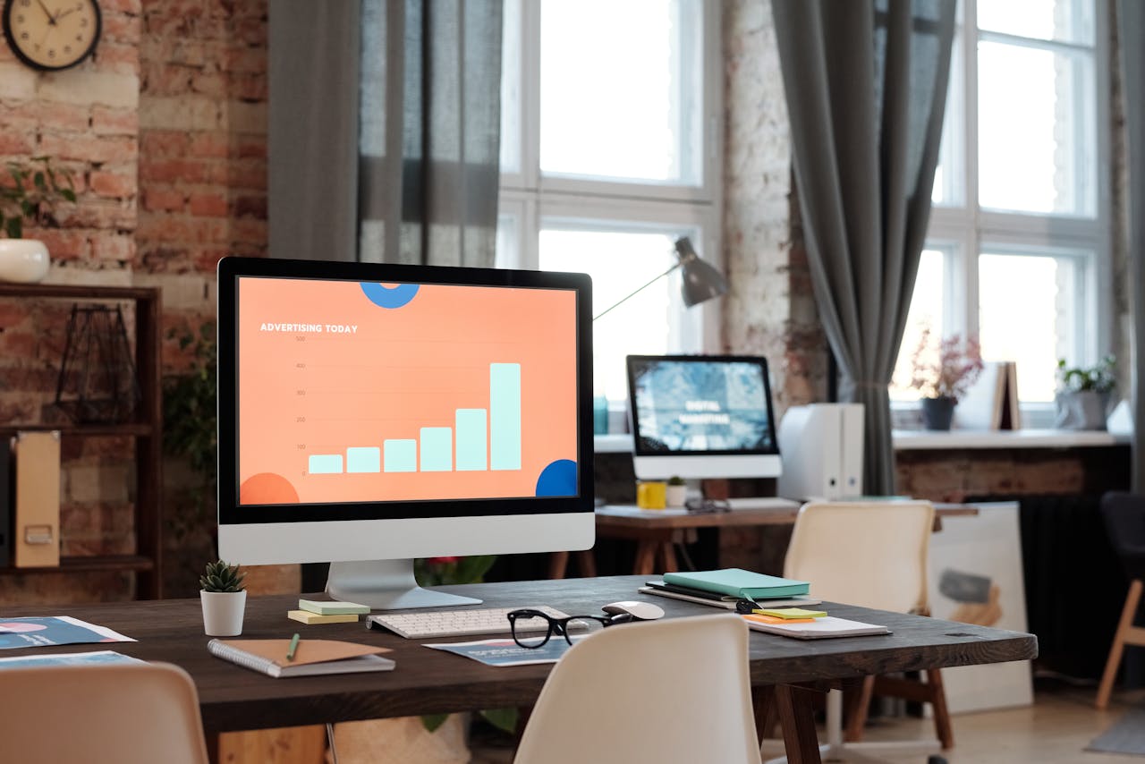 A stylish office setup featuring a computer displaying a graph on advertising trends.